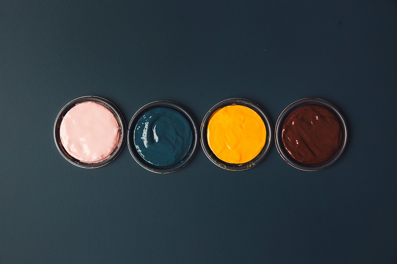 藍色桌子上充滿活力的顏料罐照片(Vibrant Pots O_愛給網(wǎng)_aigei_com